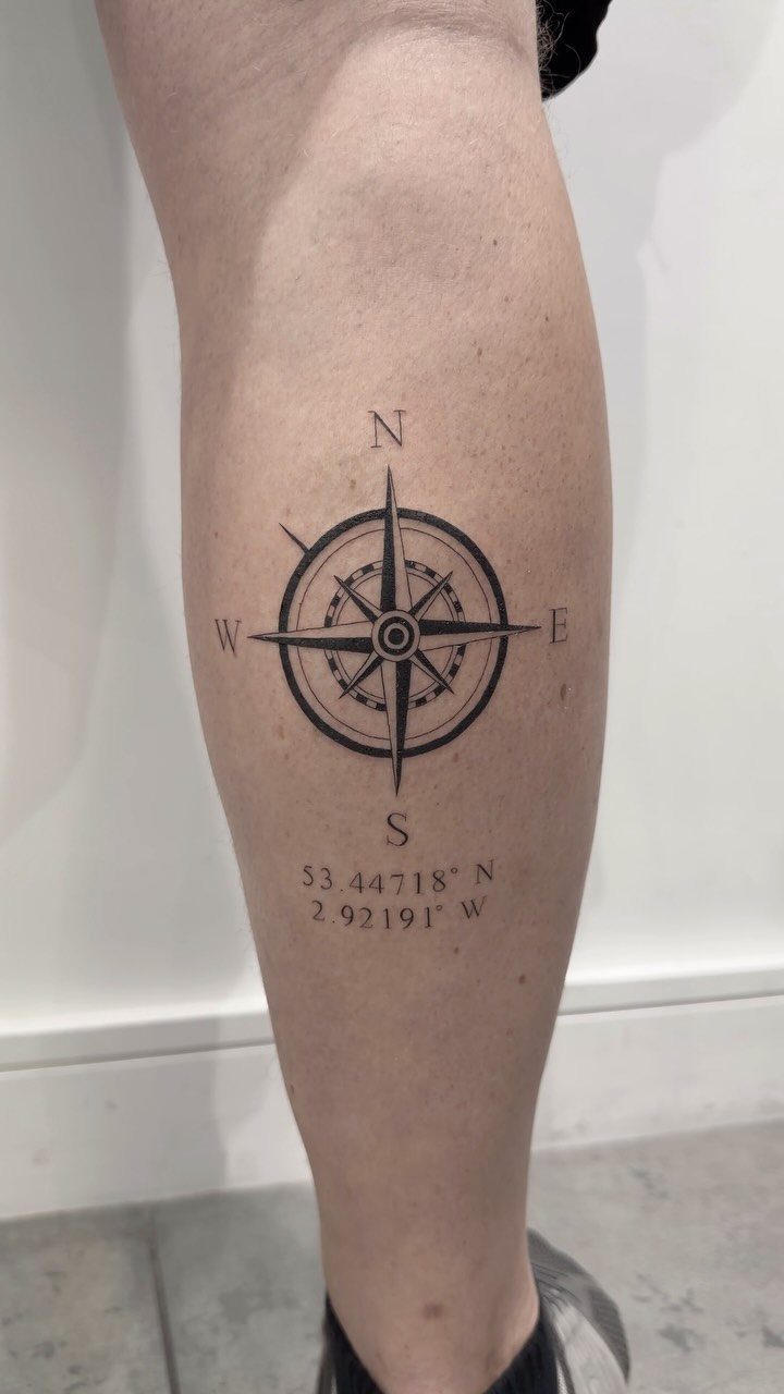 Compass rose tattoo with geographical coordinates on a person's lower leg