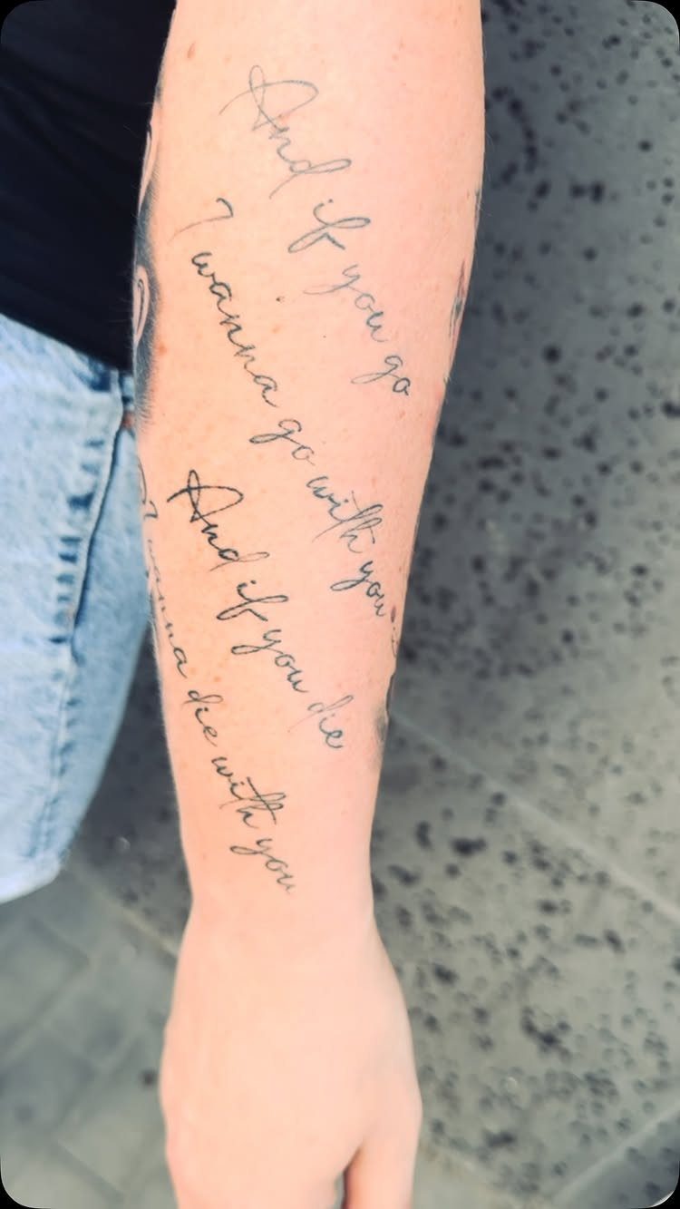 Forearm tattoo with cursive text written in black ink on fair skin.