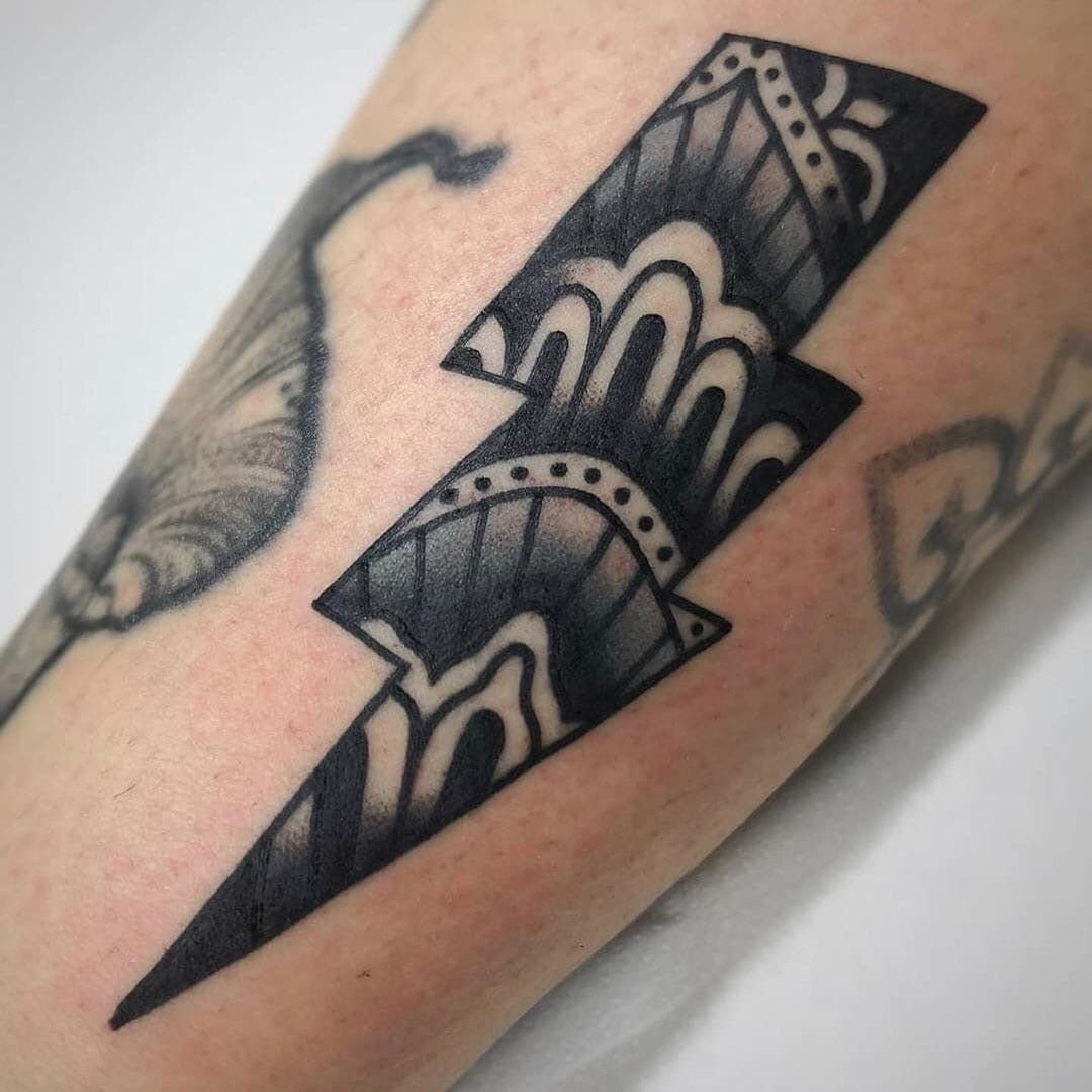 Lightning bolt tattoo with decorative patterns covering part of an older faded tattoo.