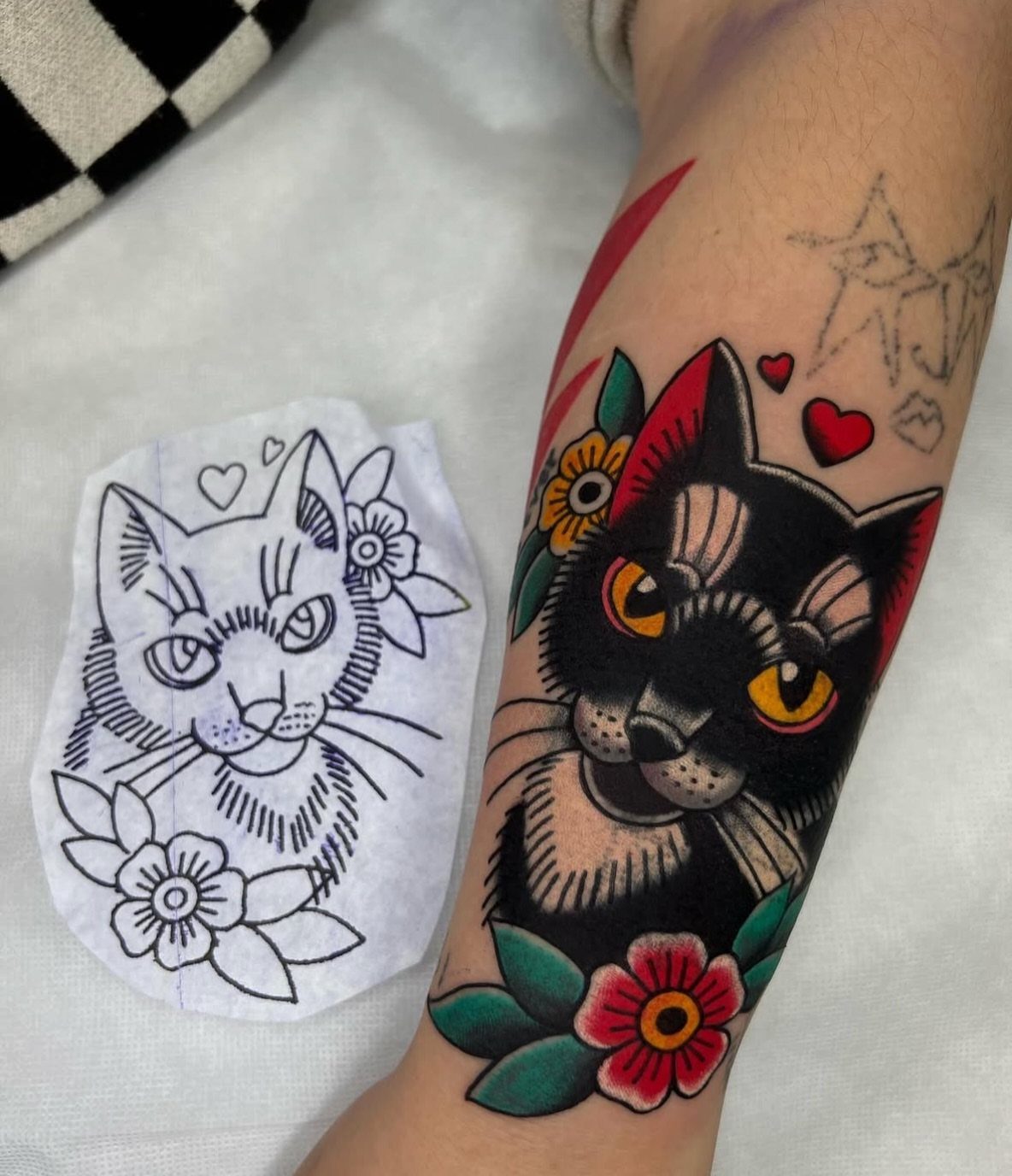 Black cat American traditional tattoo on an arm with a design stencil nearby