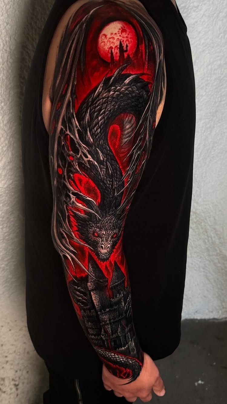Full sleeve tattoo of a black dragon and red moon on a person's arm.