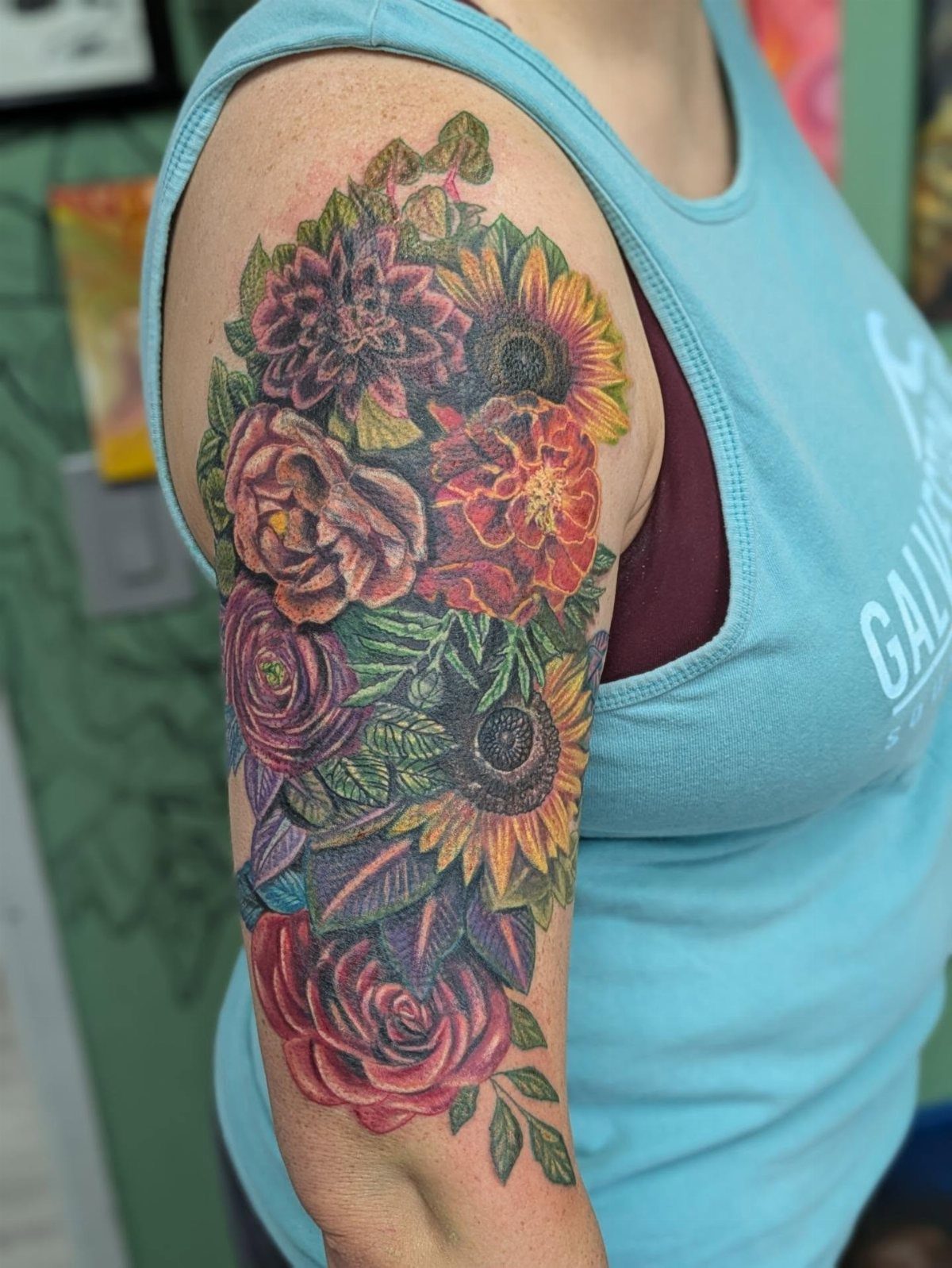 Colorful floral tattoo on an upper arm featuring red and yellow flowers.
