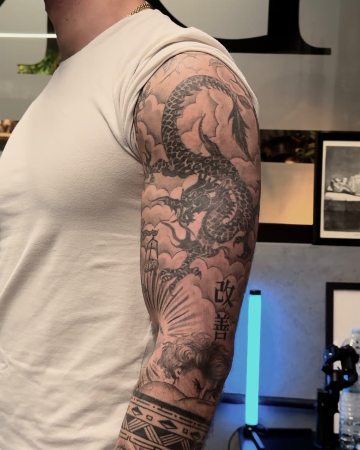 Detailed black and grey dragon tattoo covering a person's upper arm and shoulder.