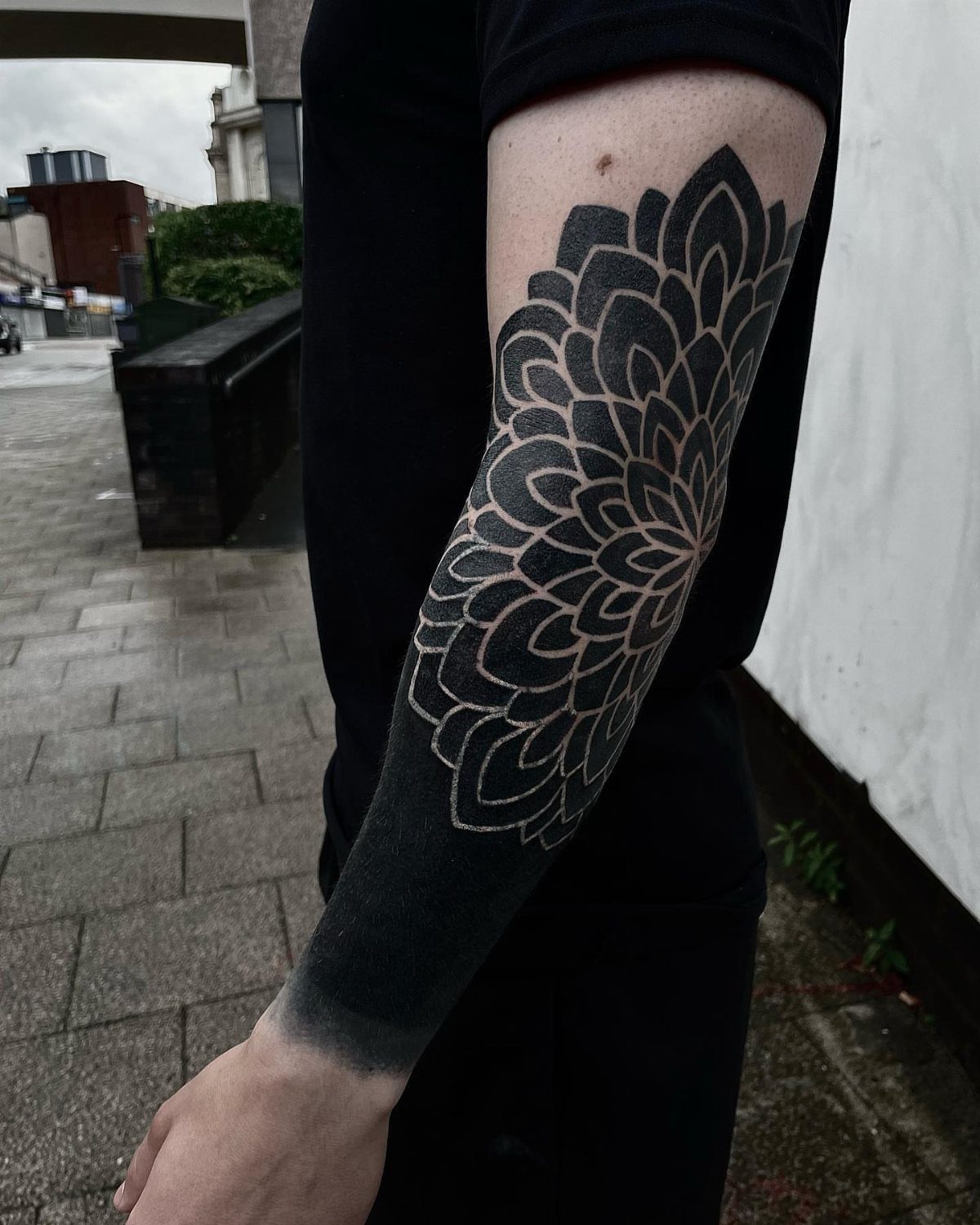 Mandala arm cover up tattoo with intricate black patterns and blackout forearm section.
