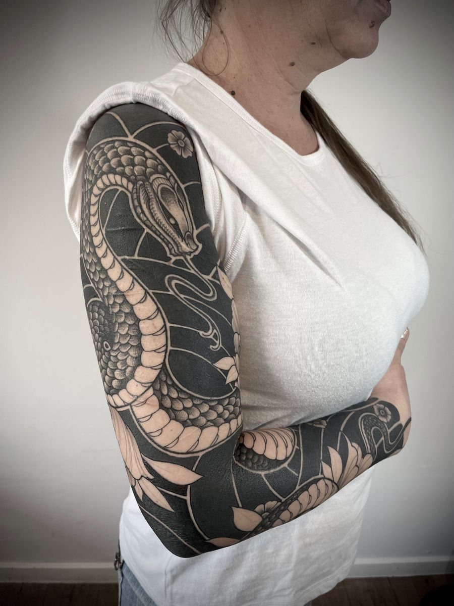 Sleeve tattoo of a large snake wrapping around a person's entire arm.