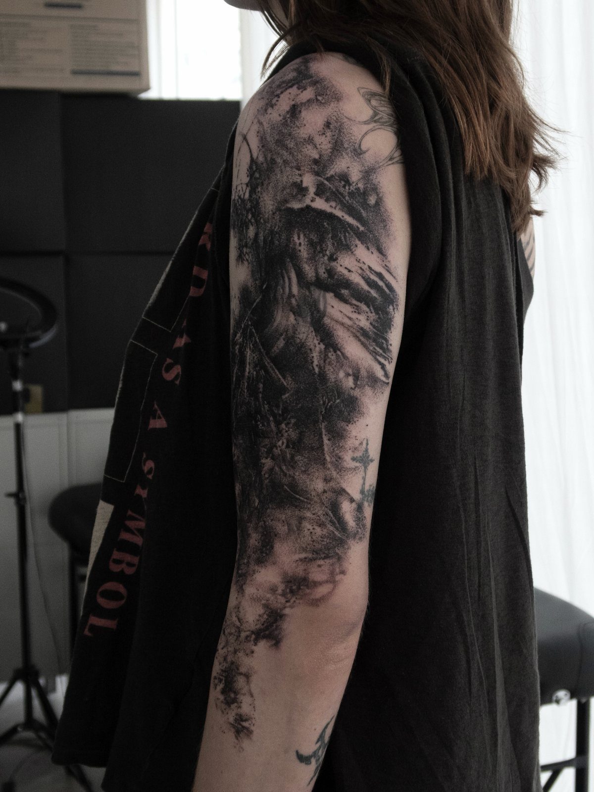 Dark black and grey tattoo covering the upper arm and forearm of a person.