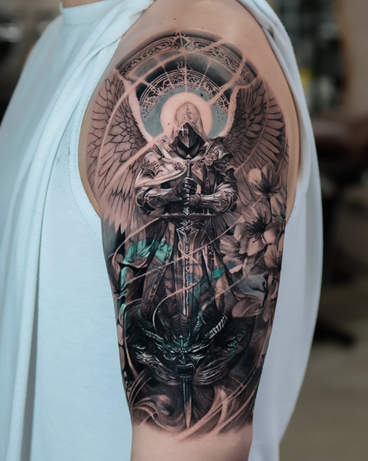 Detailed black and grey arm tattoo of a winged knight and demon.
