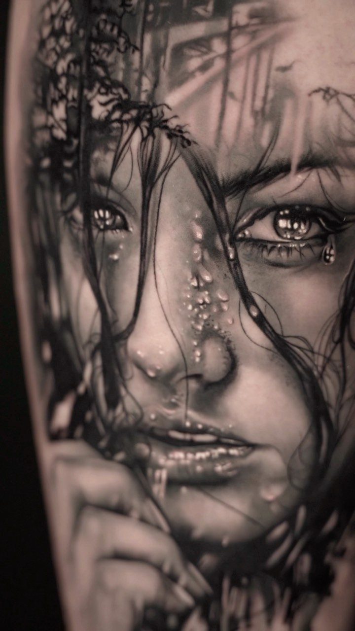 Woman's face tattoo in black ink with water droplets and wet hair.