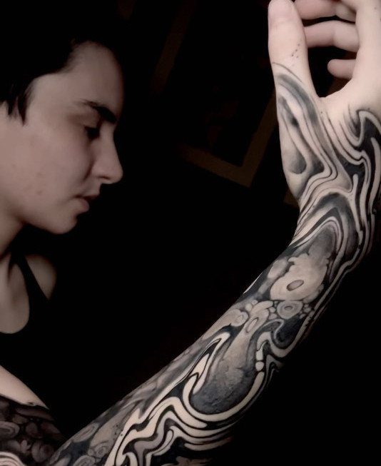 Abstract blackwork sleeve tattoo with swirling patterns covering a person's arm and hand.