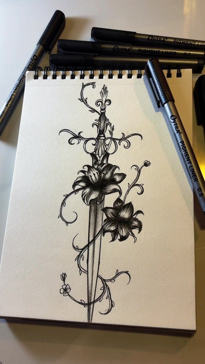 Sword entwined with lilies and curling vines drawn in black ink in a notebook.