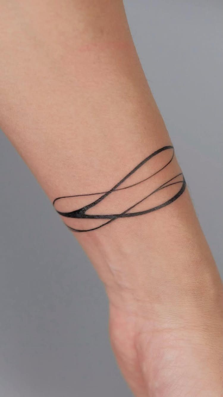 Black ink tattoo of flowing curved lines wrapped around a person's wrist.