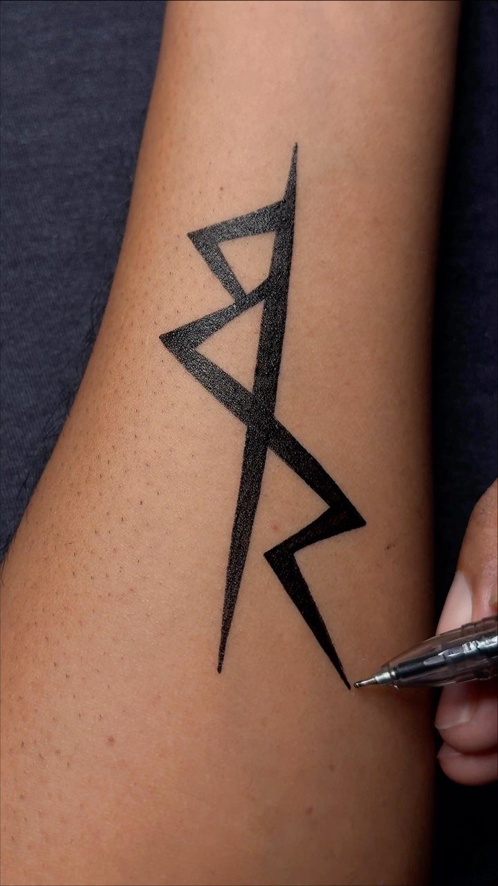 Angular black ink symbol drawn on a person's arm with a black pen.