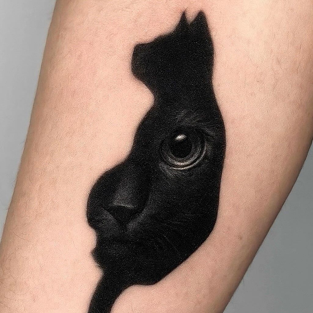 Black cat tattoo on an arm featuring realistic fur texture and a detailed eye