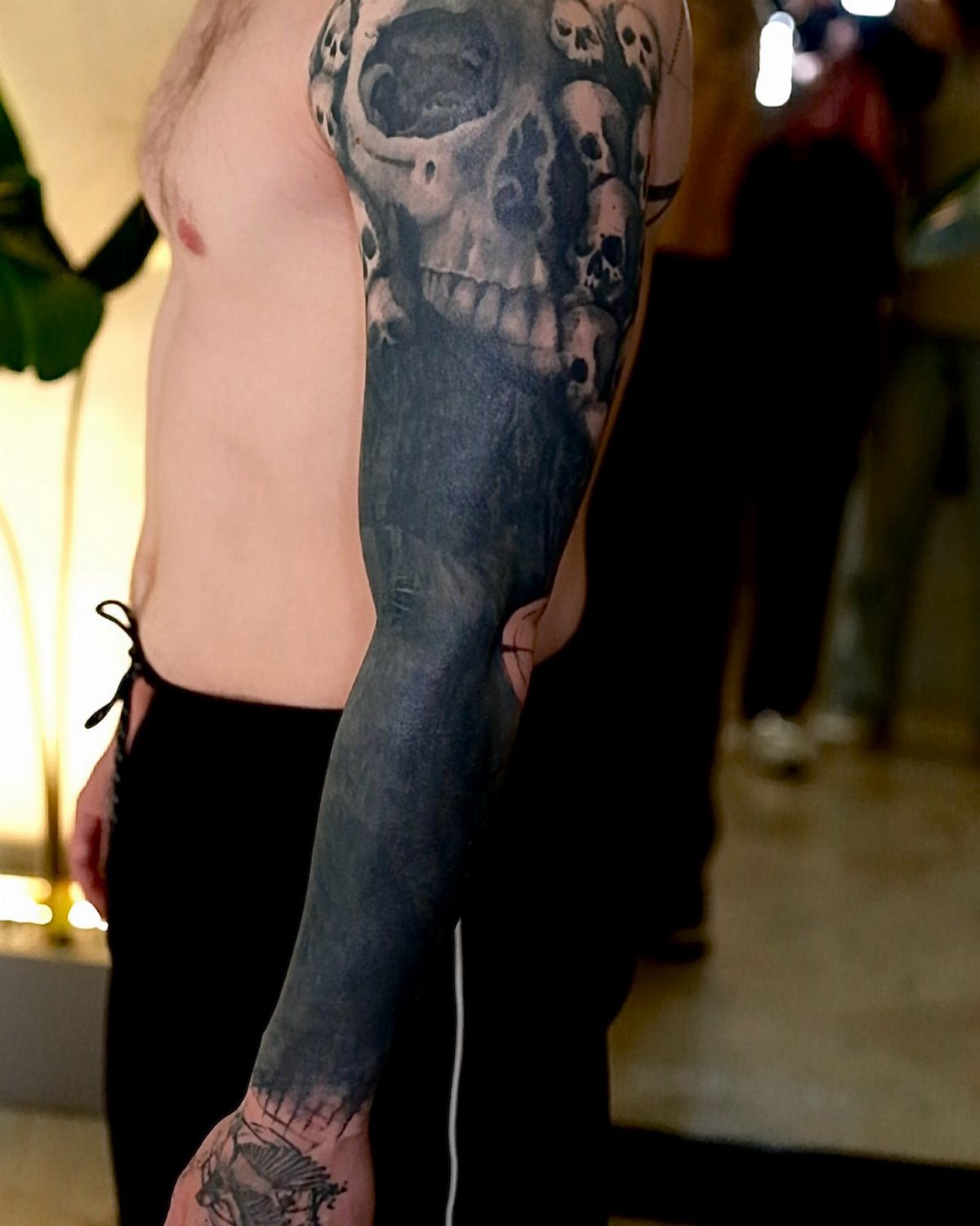 Arm with a skull tattoo and a solid black ink cover-up sleeve.