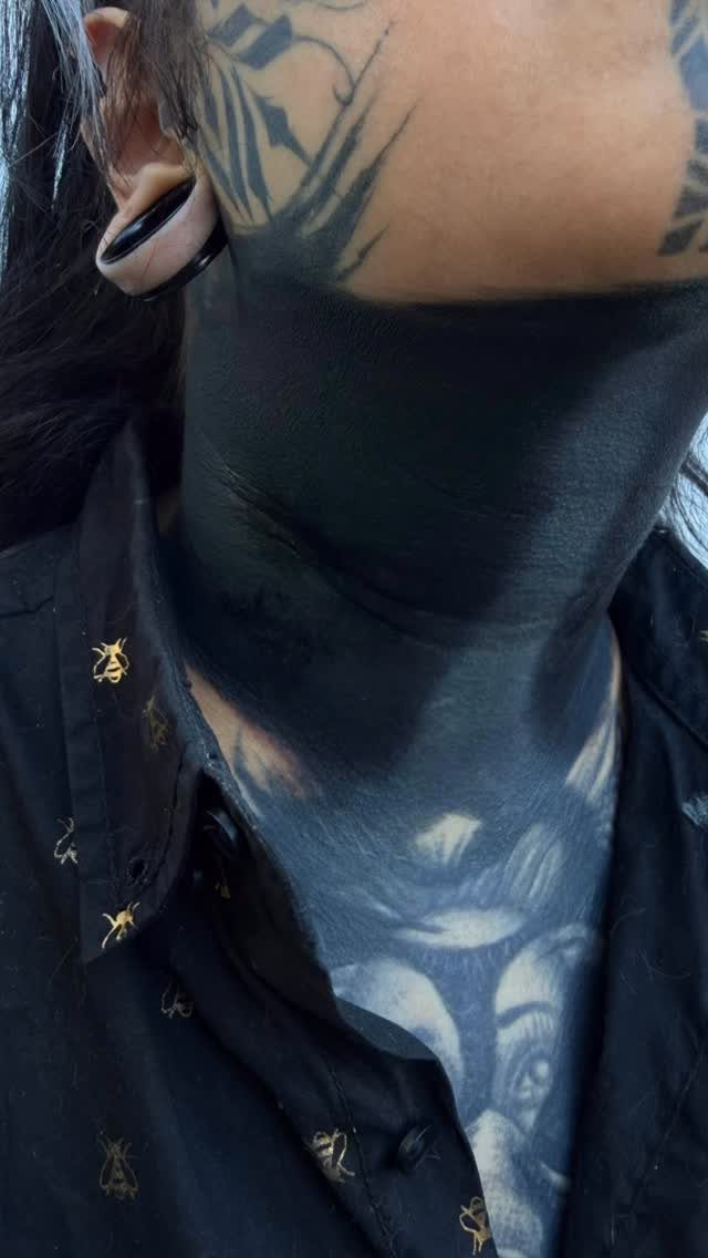 Solid black ink tattoo covering the entire neck of a person.