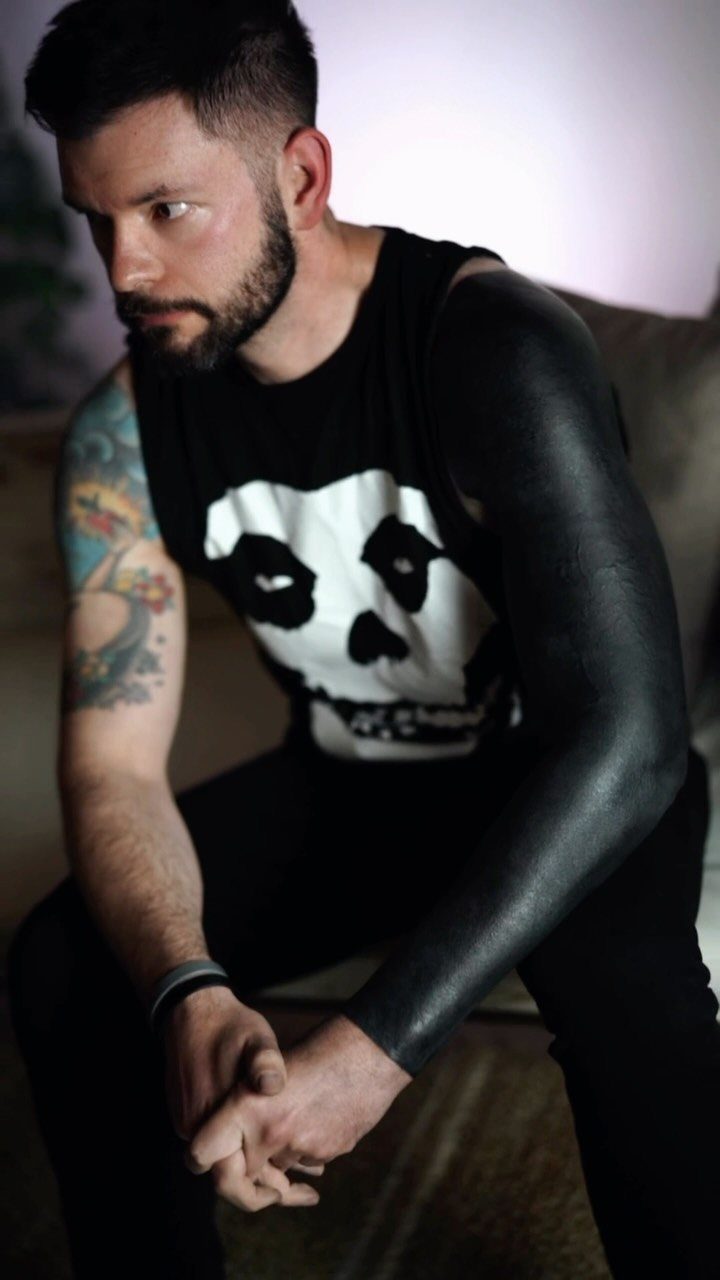 Man with a solid black blackout tattoo covering his entire left arm.