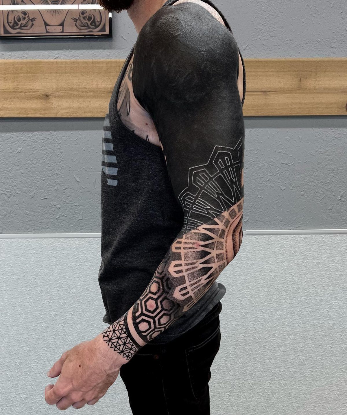 Arm with a blackout cover up tattoo featuring complex geometric and hexagonal patterns.