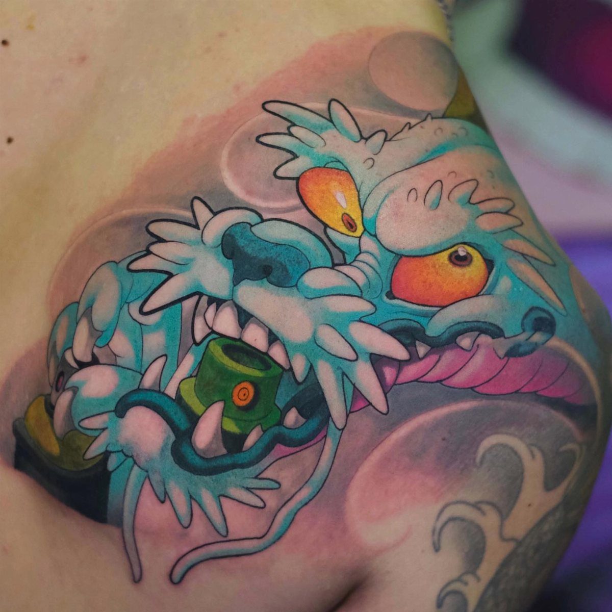 Blue dragon head tattoo with orange eyes on a person's skin.