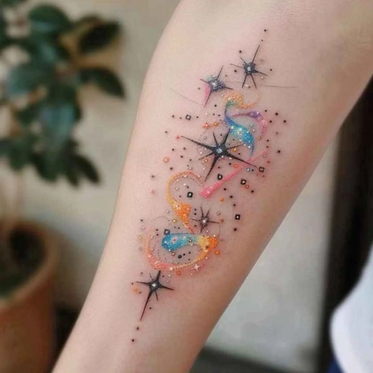 Cosmic tattoo with colorful swirls and stars on a person's forearm