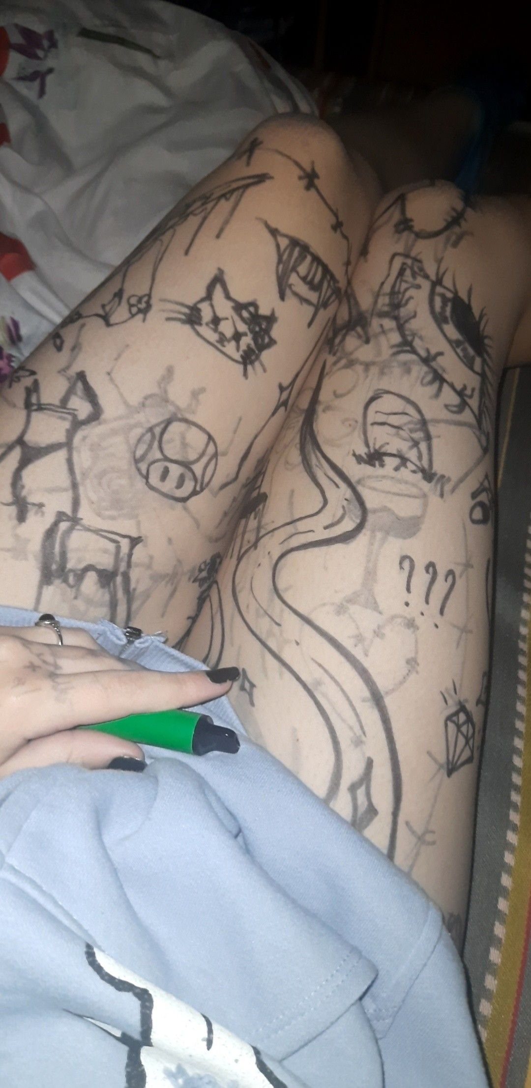 Black ink pen doodles and drawings covering a person's thighs and legs.