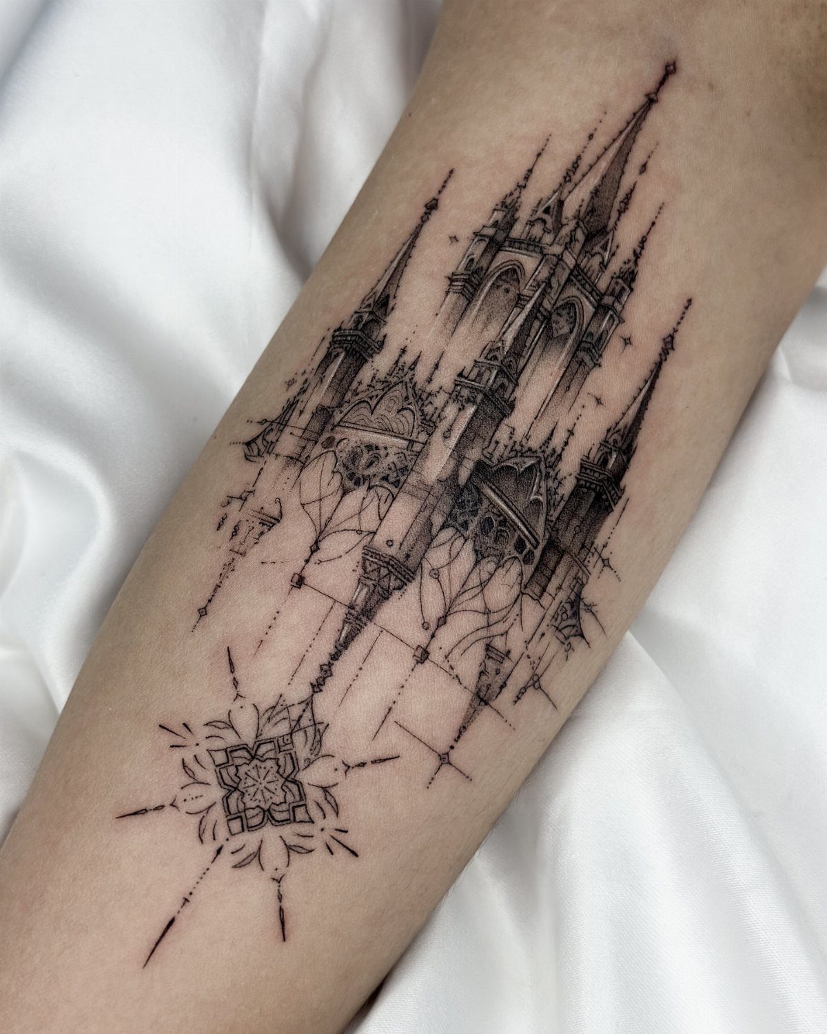 Gothic fantasy castle tattoo with tall spires and geometric symbol on a forearm.