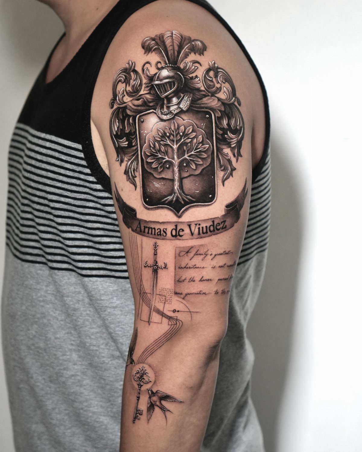 Heraldic family crest tattoo on an arm featuring a shield with a tree.