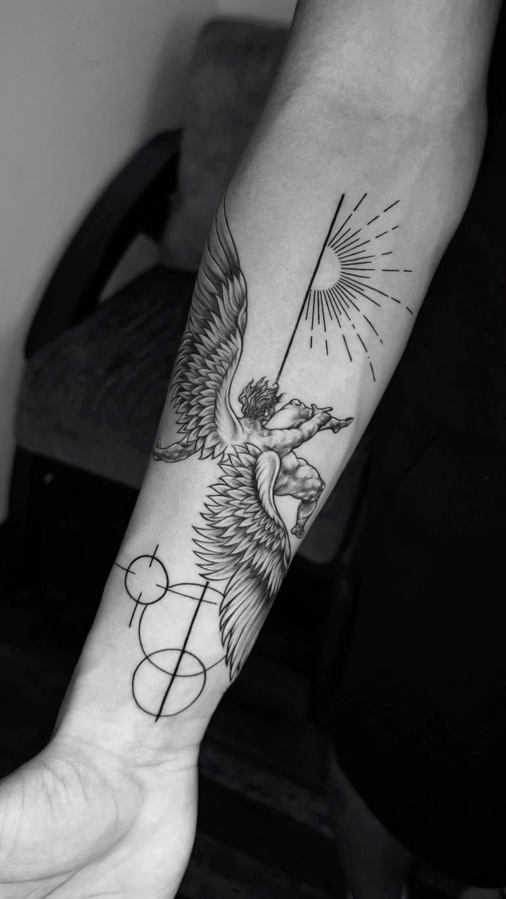 Forearm tattoo of a winged angel surrounded by geometric circles and radiating lines.