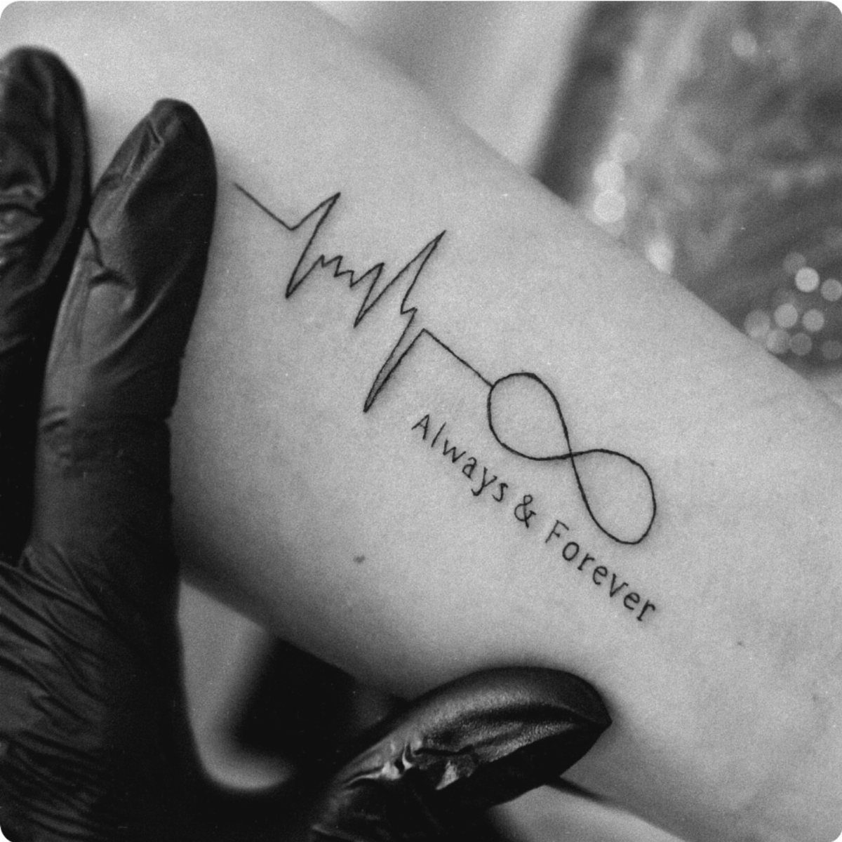 Heartbeat line tattoo transitioning into an infinity symbol with the text Always & Forever.