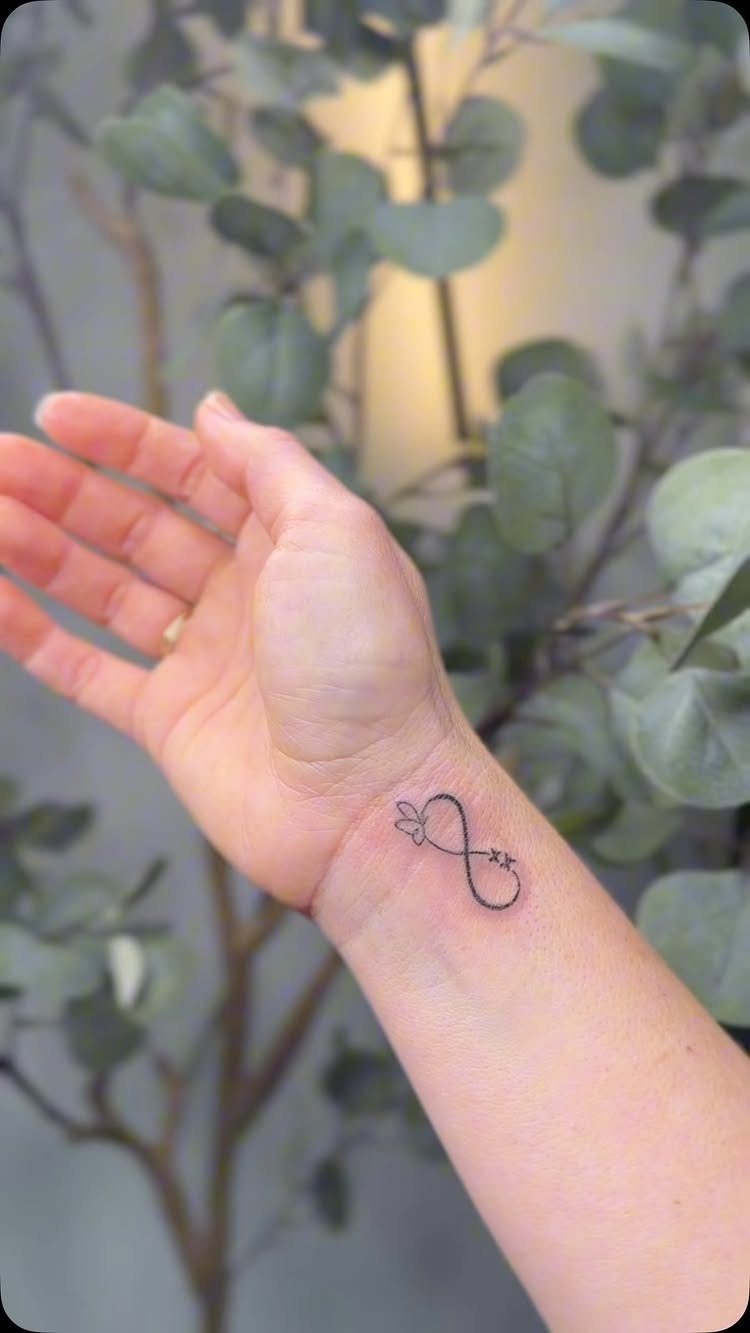 Infinity symbol tattoo with a small heart on a person's inner wrist.