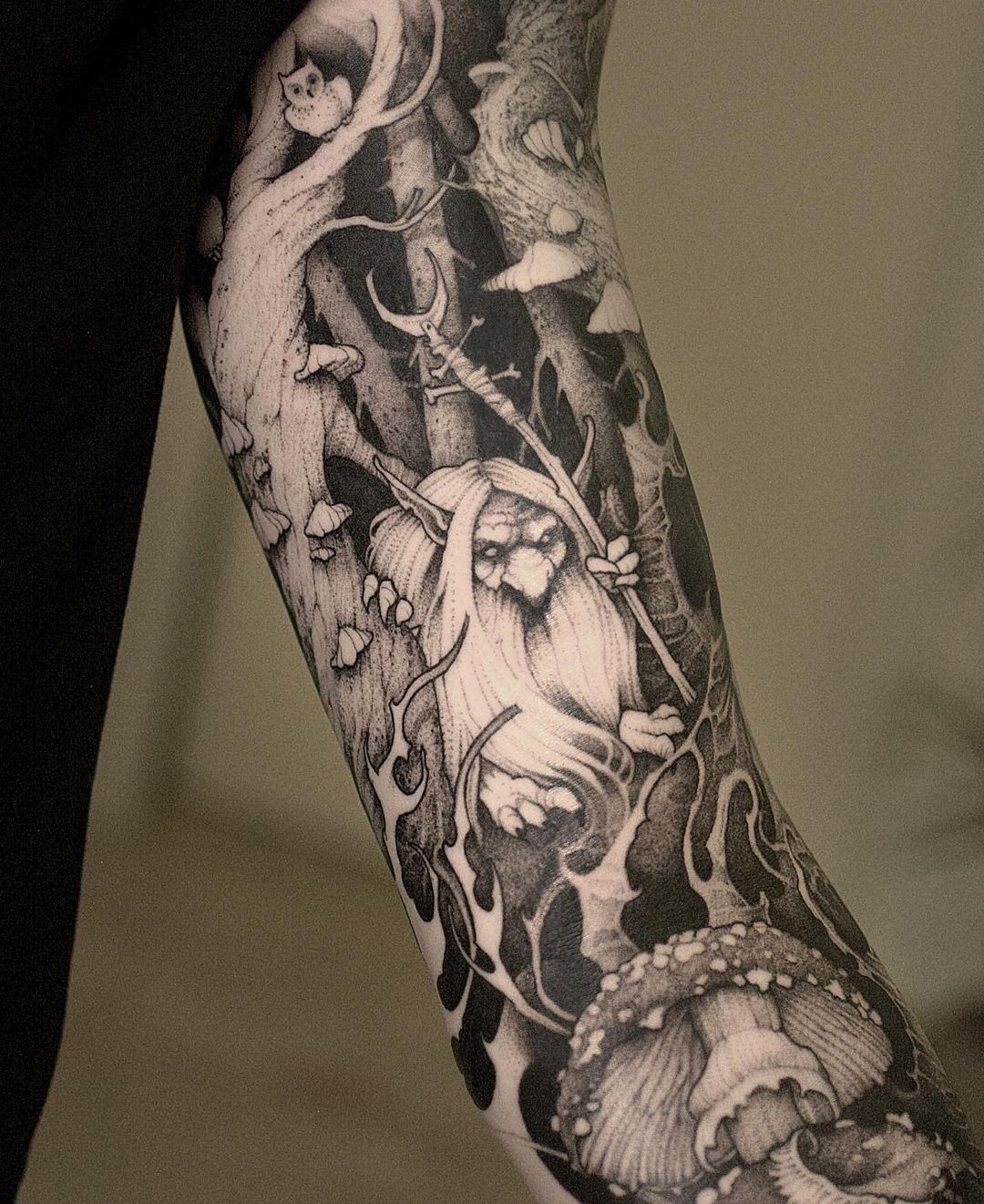 Mythical creature tattoo on an arm featuring a bearded figure with a staff in a forest