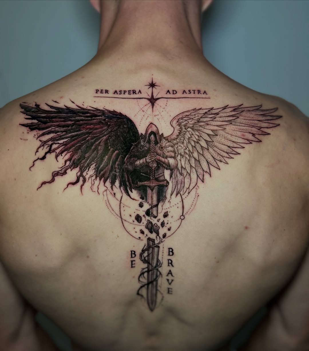 Detailed back tattoo of a sword and contrasting dark and light wings.