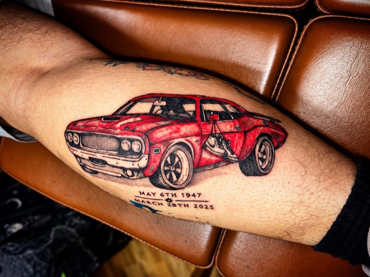 Red classic car tattoo on a forearm with memorial dates written underneath.