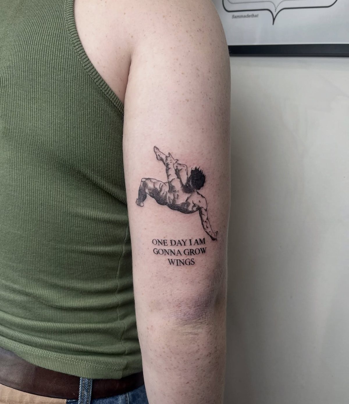 Tattoo on an arm showing a falling person and the quote about growing wings.