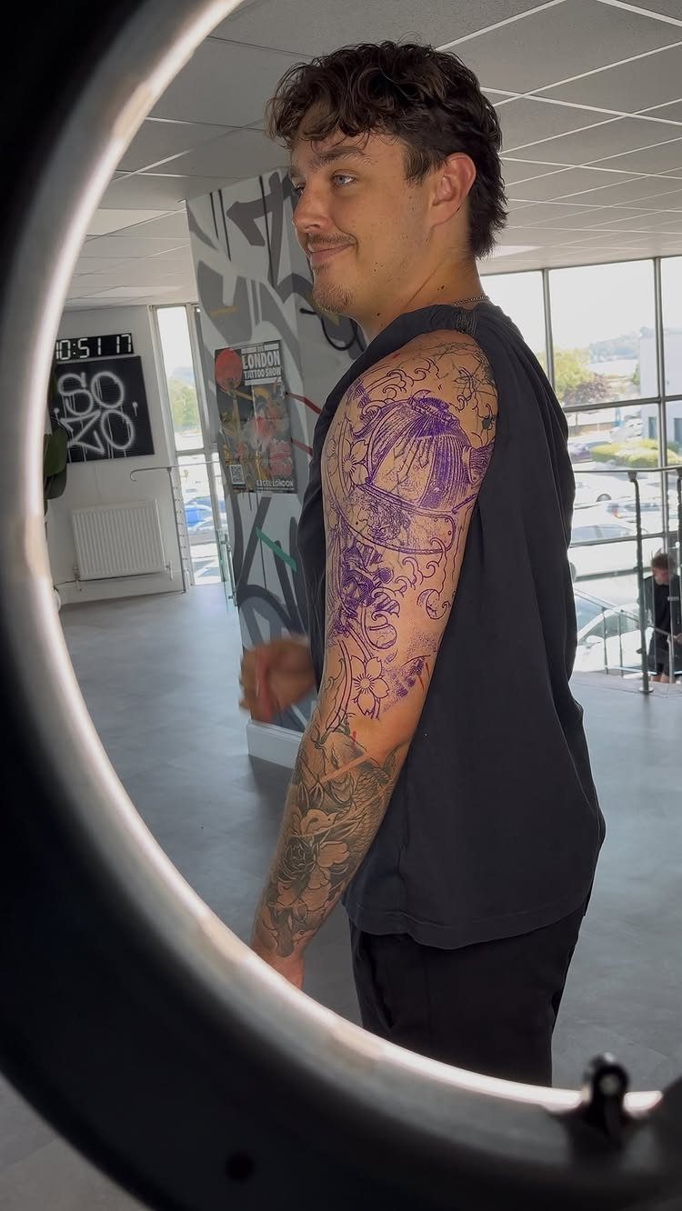 Man with a purple tattoo stencil on his arm covering an old tattoo.