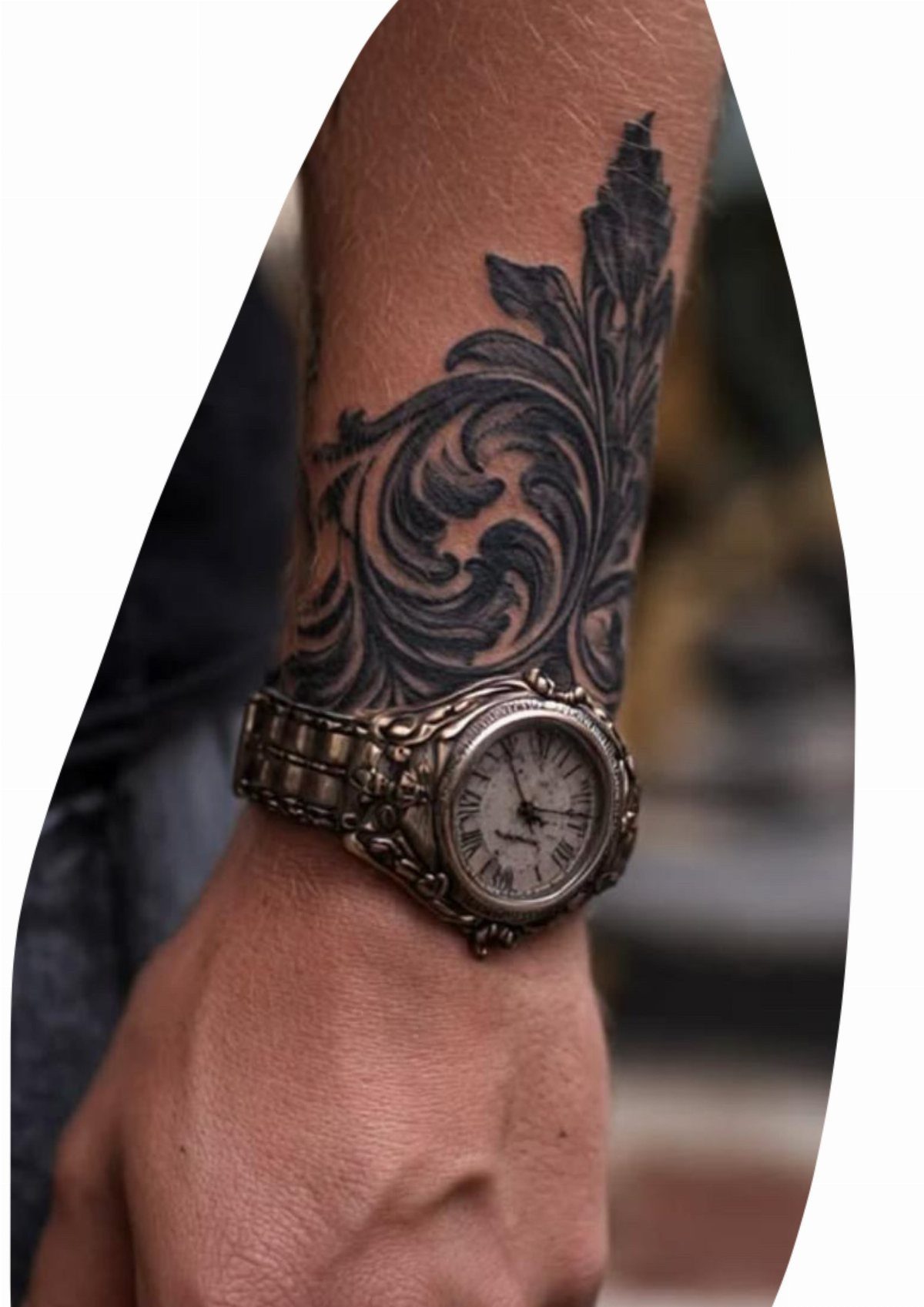 Ornate black ink scrollwork tattoo on a wrist wearing a silver watch