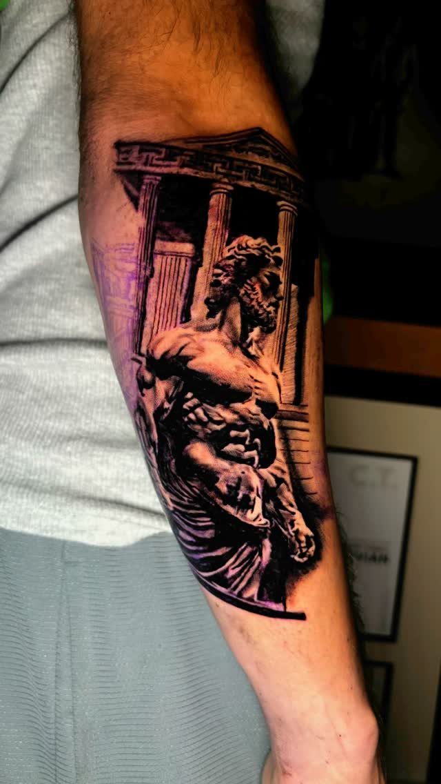 Mythological figure tattoo on a man's forearm featuring a muscular god and Greek columns.