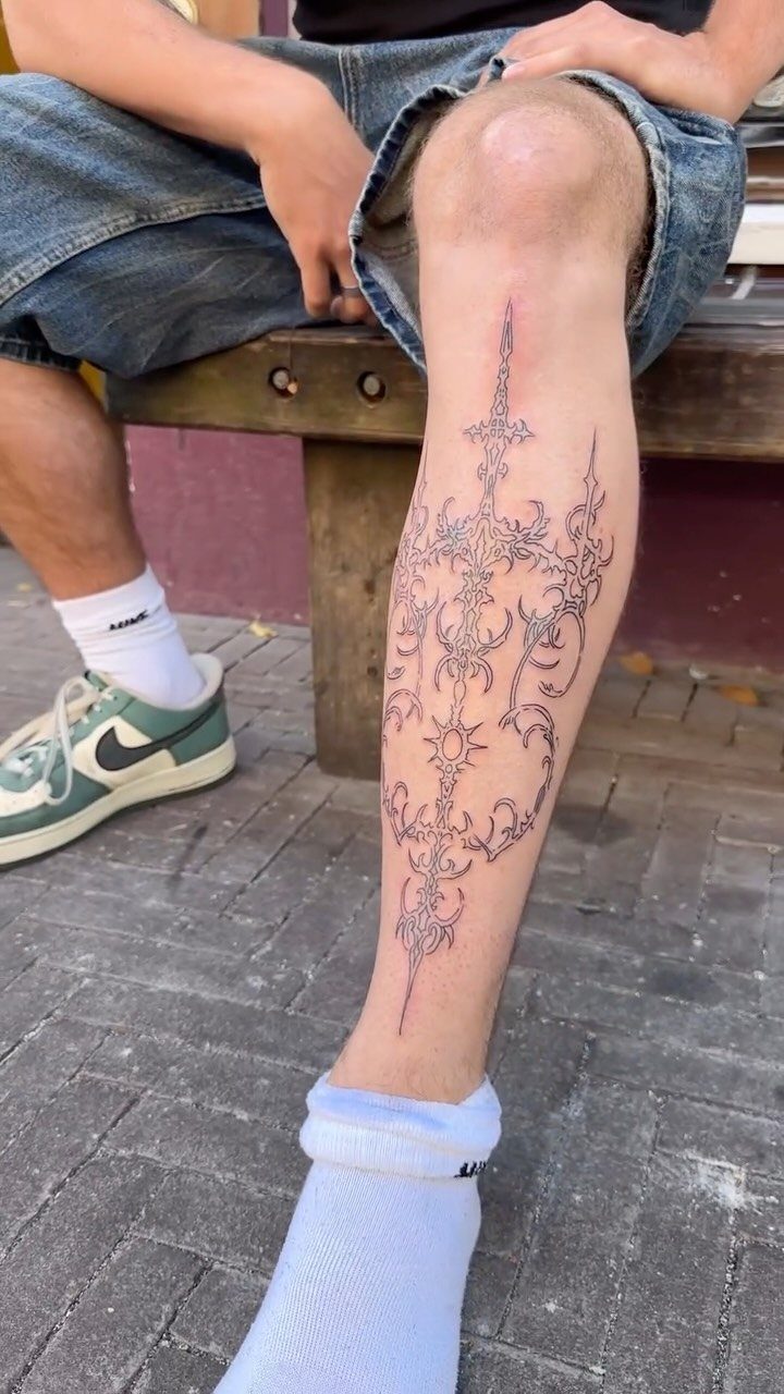 Intricate black ink filigree tattoo on a person's lower leg and shin.