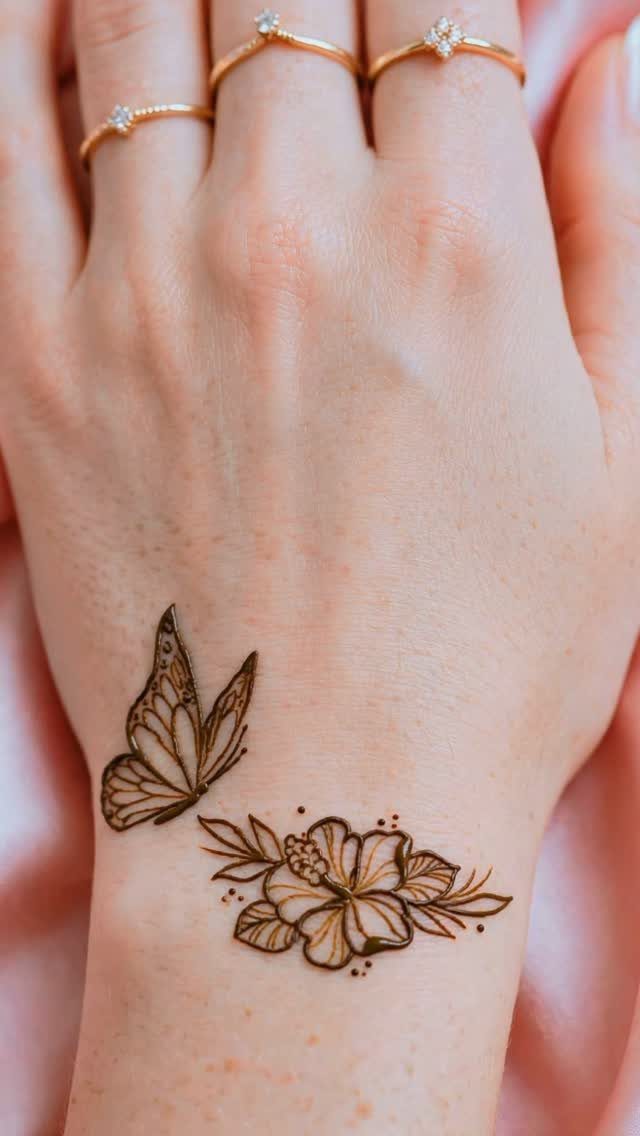 Henna tattoo of a butterfly and flower on a person's wrist and hand.