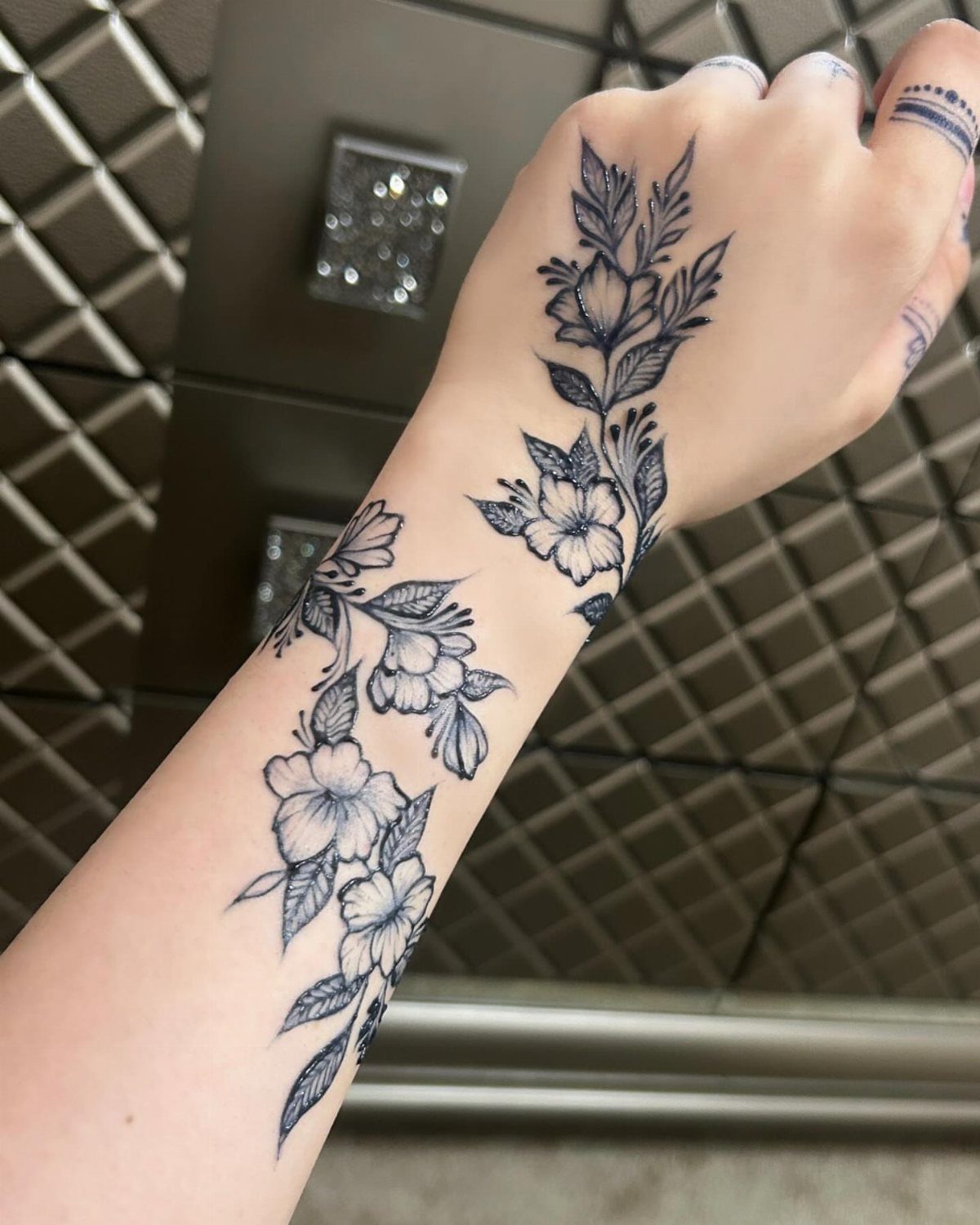 Floral vine tattoo with blossoms winding up a person's forearm and wrist.