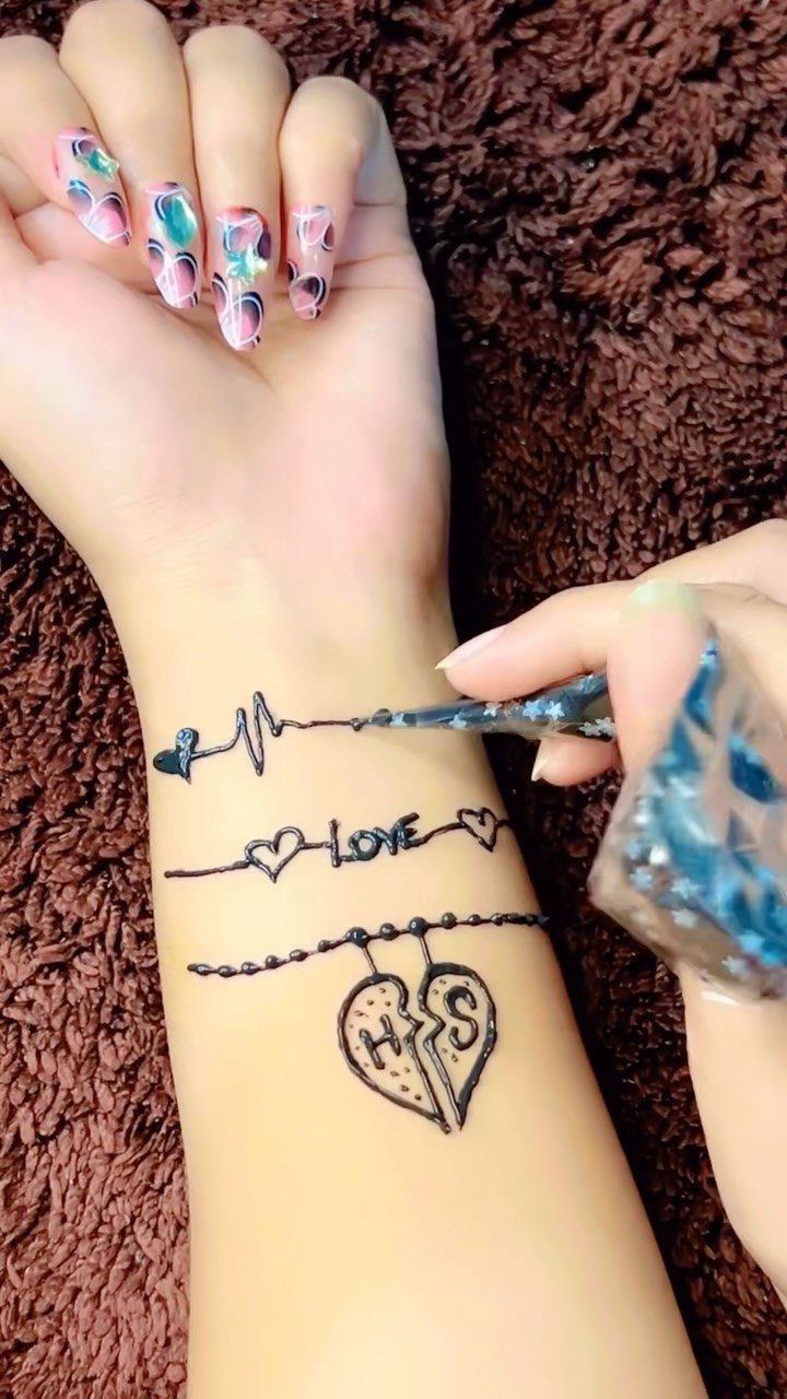 Henna tattoo on a wrist featuring a heartbeat, love text, and broken heart.