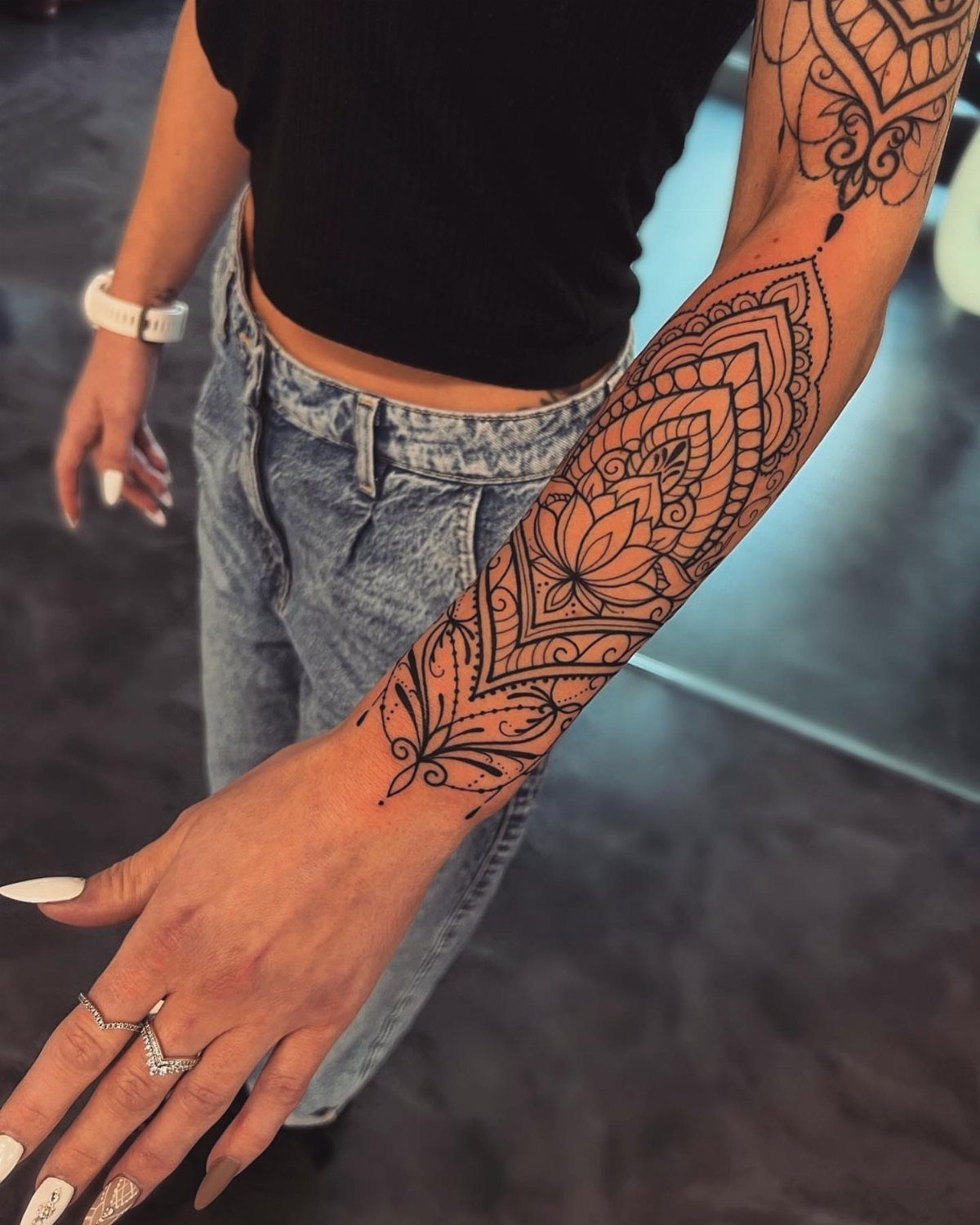 Intricate black henna mandala tattoo on a person's forearm and wrist.