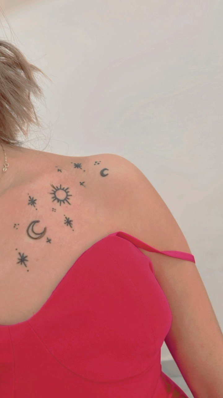 Sun, moon, and star tattoos on a person's upper back and shoulder.