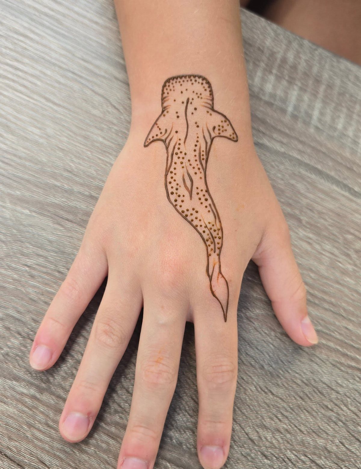 Whale shark henna tattoo on the back of a person's hand and wrist.