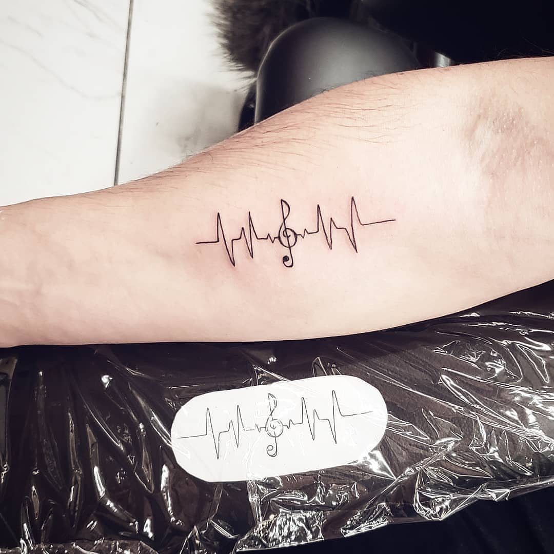 Heartbeat line tattoo with a treble clef on a person's forearm