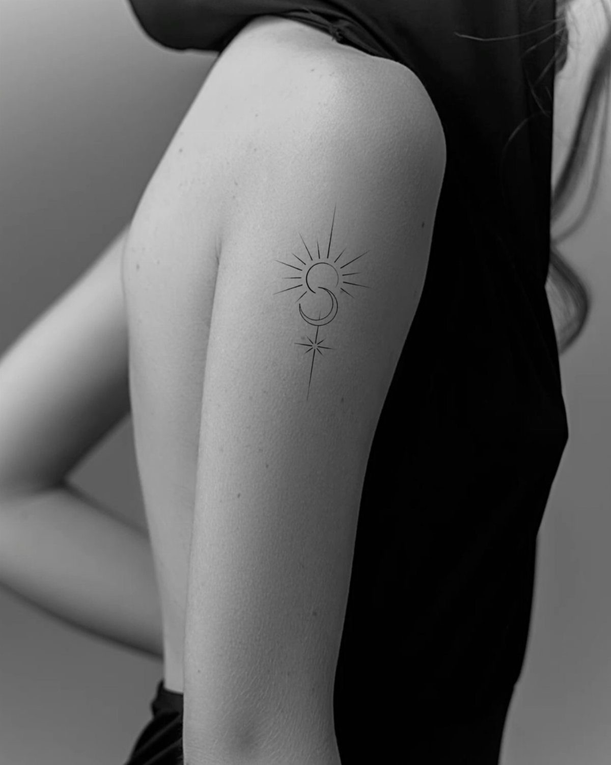 Minimalist tattoo of the letter S with radiating lines on an upper arm.