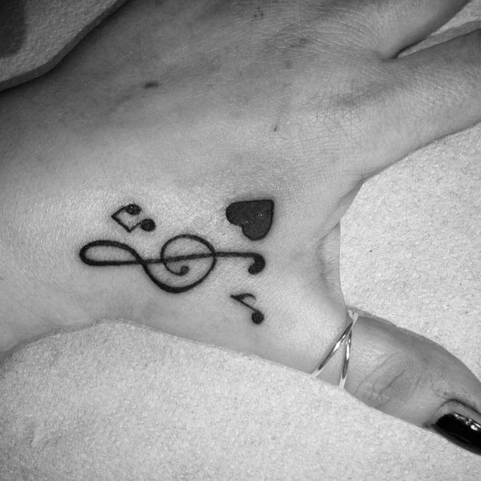 Music note and heart tattoo on the back of a person's hand