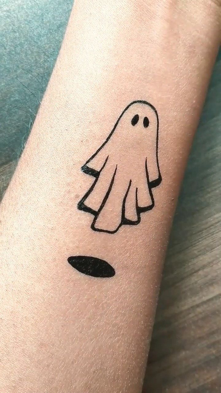 Small black ink ghost drawing on a person's forearm with a small shadow.