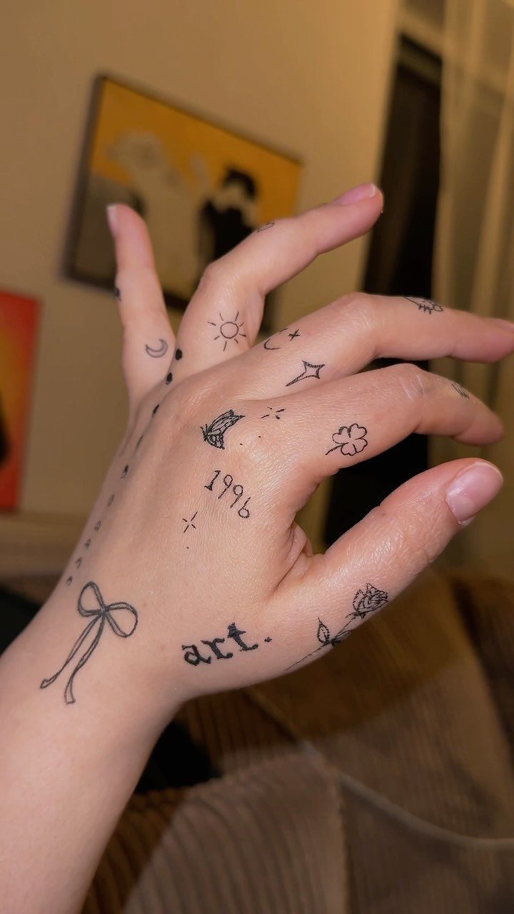 Hand and wrist decorated with small black ink drawings of symbols and text.