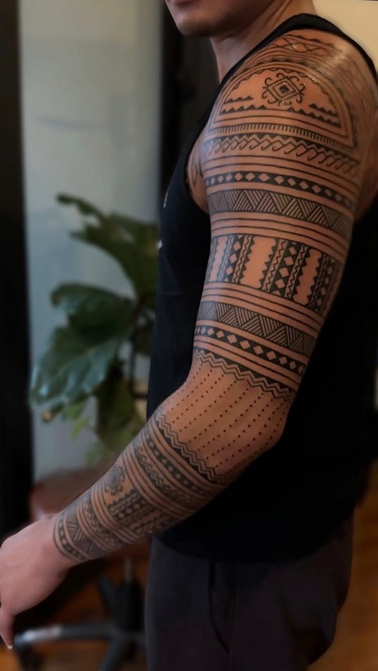 Man's arm with a full sleeve of black geometric tribal tattoo patterns