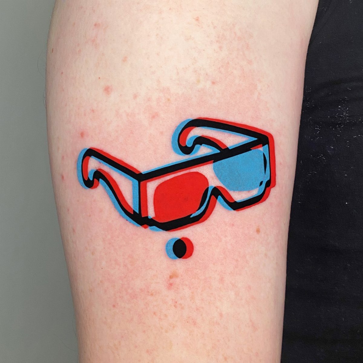 3D glasses tattoo with red and blue anaglyph effect on a person's arm